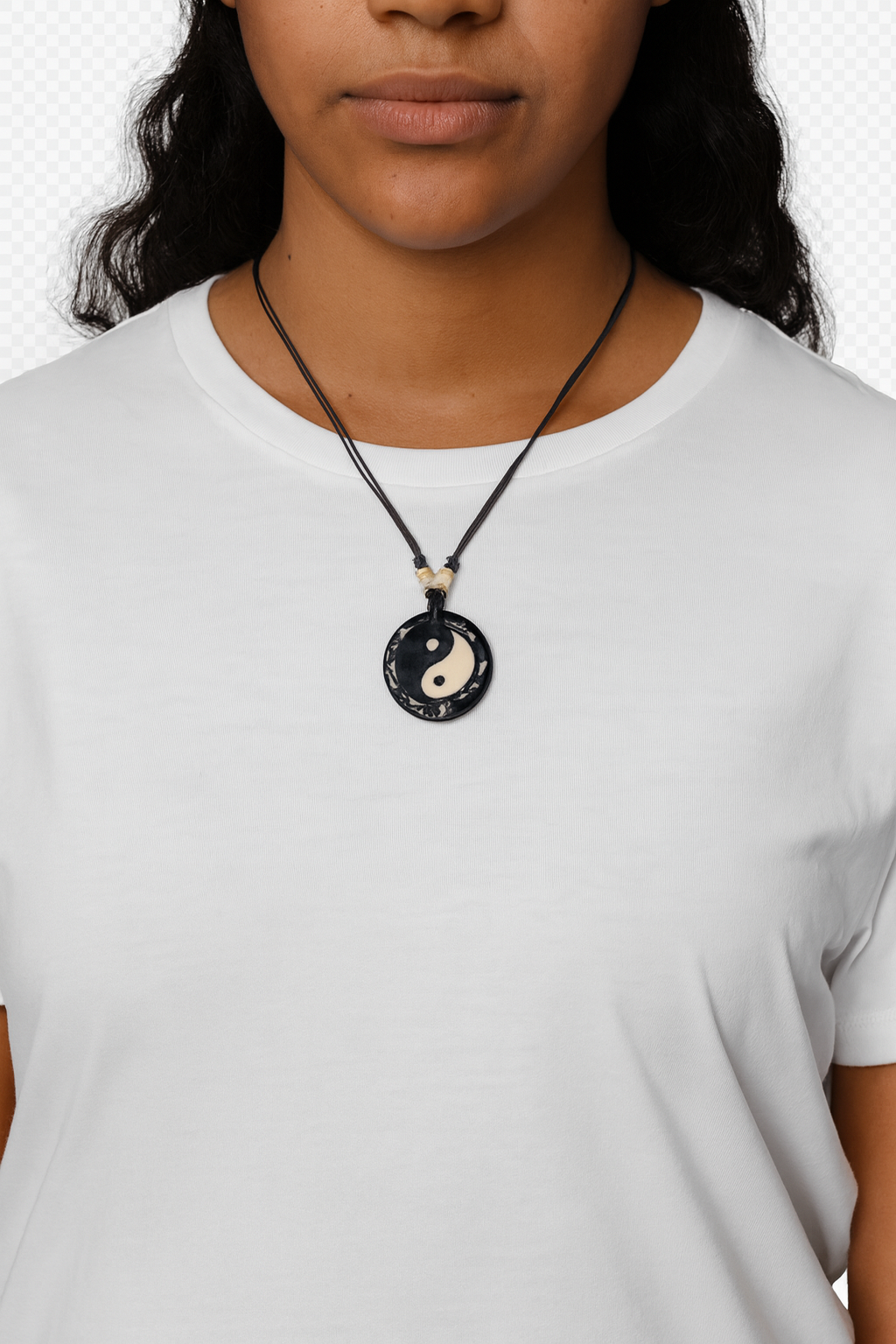 Person wearing a necklace with a yin yang pendant on a plain background