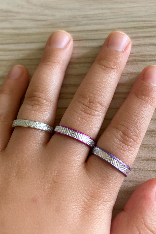 An image of a child’s hand with coloured aluminium rings on the fingers 