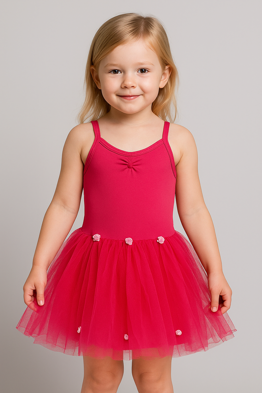 Young girl wearing a dark pink long tutu dress on a plain background