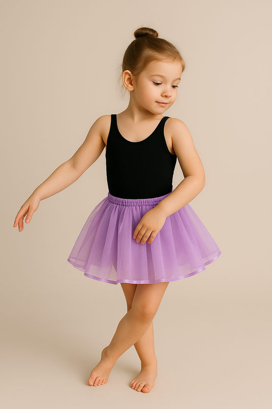 Young girl in a black leotard and flamigno tutu dancing on a beige background